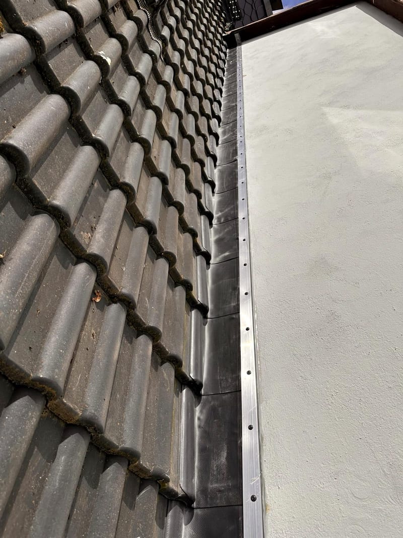 Wandanschluss zwischen Ziegeldach und verputzter Wand mit Aluminium-Abschlussprofil